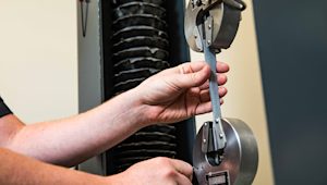A close-up of a tensile strength testing machine evaluating the durability and flexibility of a material sample.